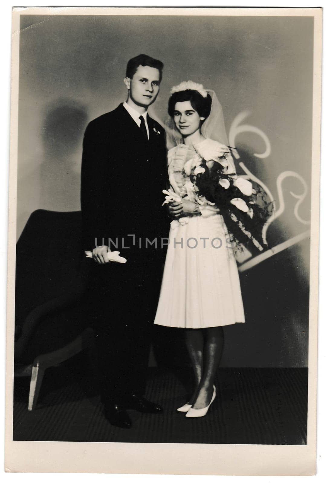 Retro photo shows bride with white kala flowers and groom wears a dark suit and white gloves. Black and white vintage photography of wedding couple. by roman_nerud