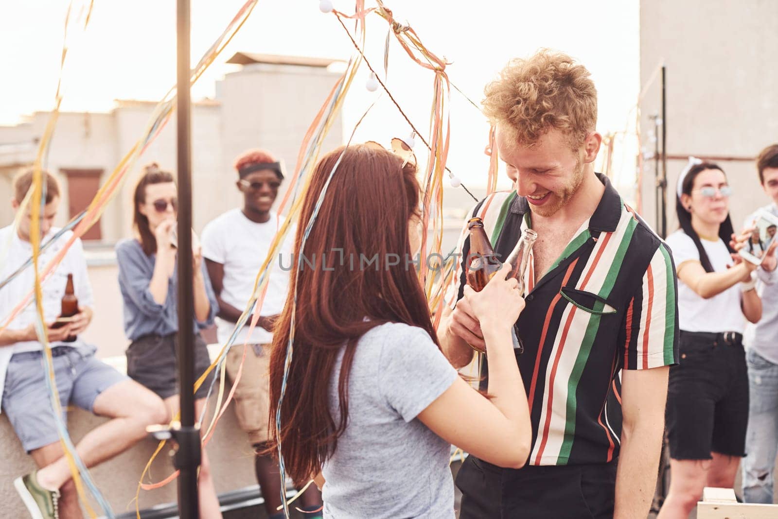 Happy couple. Group of young people in casual clothes have a party at rooftop together at daytime.