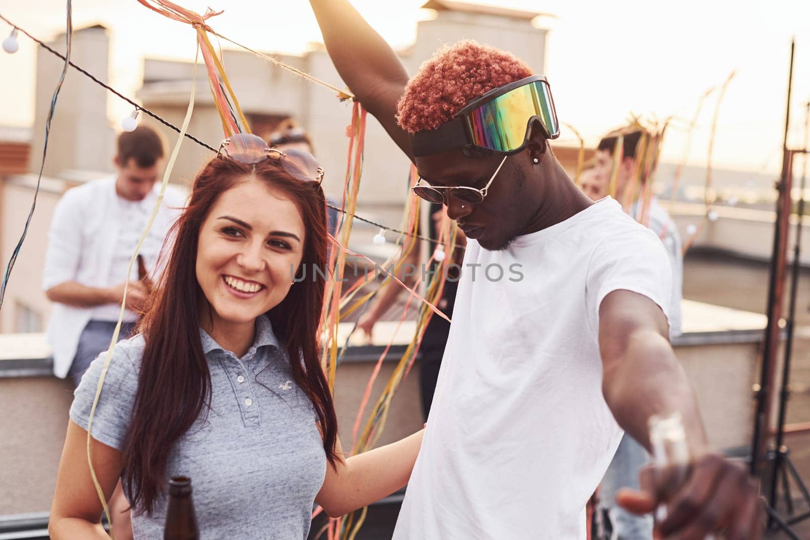 Happy multiracial couple. Group of young people in casual clothes have a party at rooftop together at daytime.