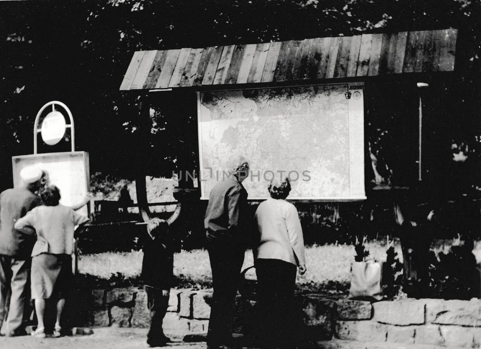 Retro photo shows people look at the touristic map. Black & white vintage photography by roman_nerud