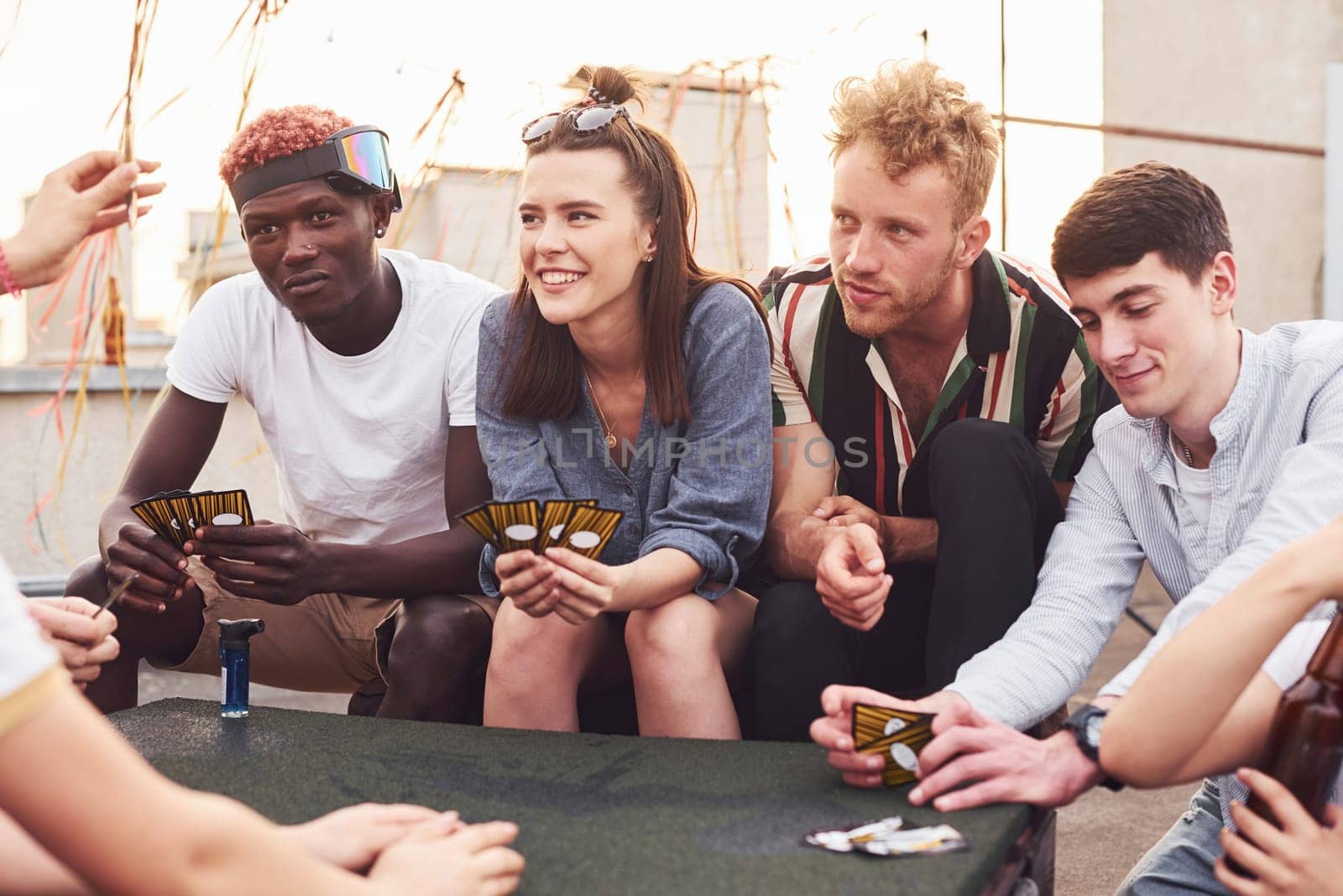 Group of young people in casual clothes have a party at rooftop together at daytime.