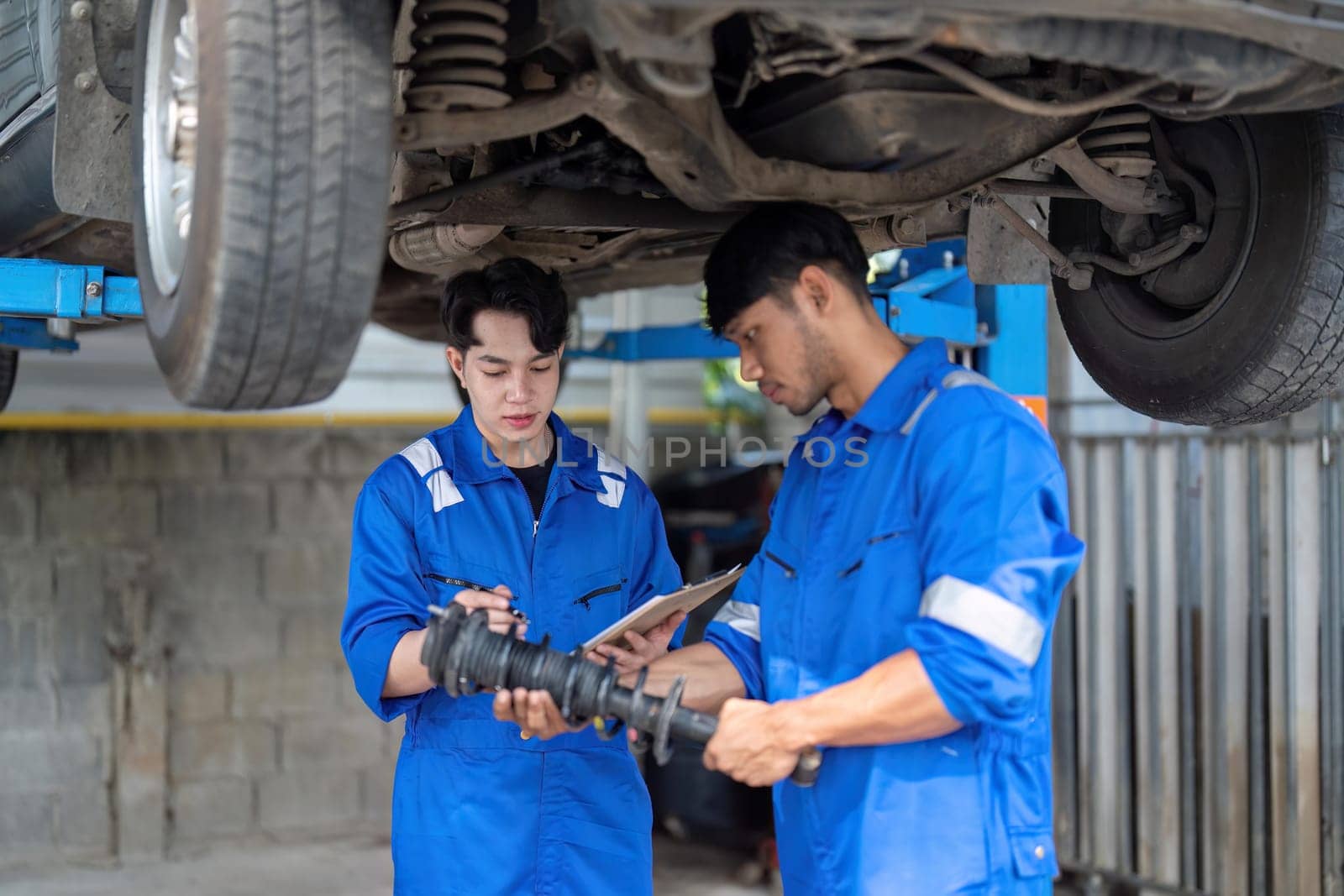 car mechanic car suspension detail of lifted automobile at repair service station by nateemee