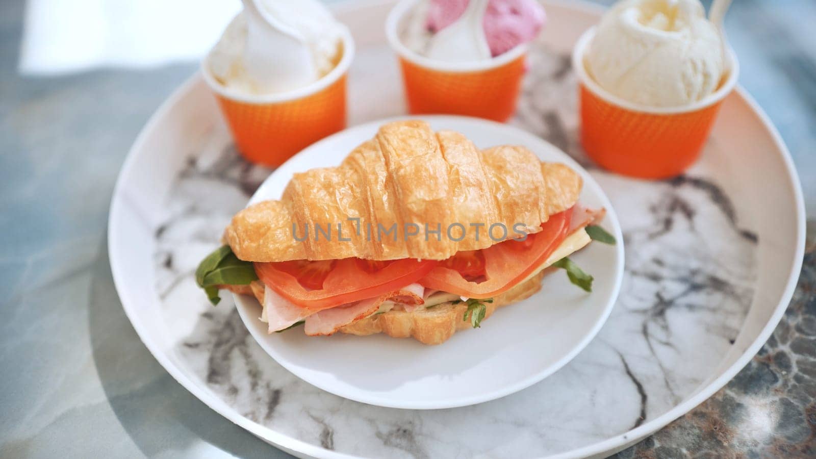 Ice cream and croissant with meat on the plate at the cafe