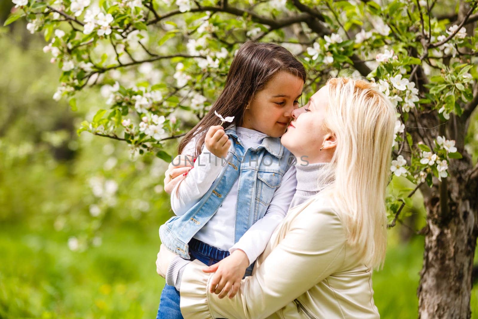 Happy woman and child in the blooming spring garden. Mothers day holiday concept. by Andelov13