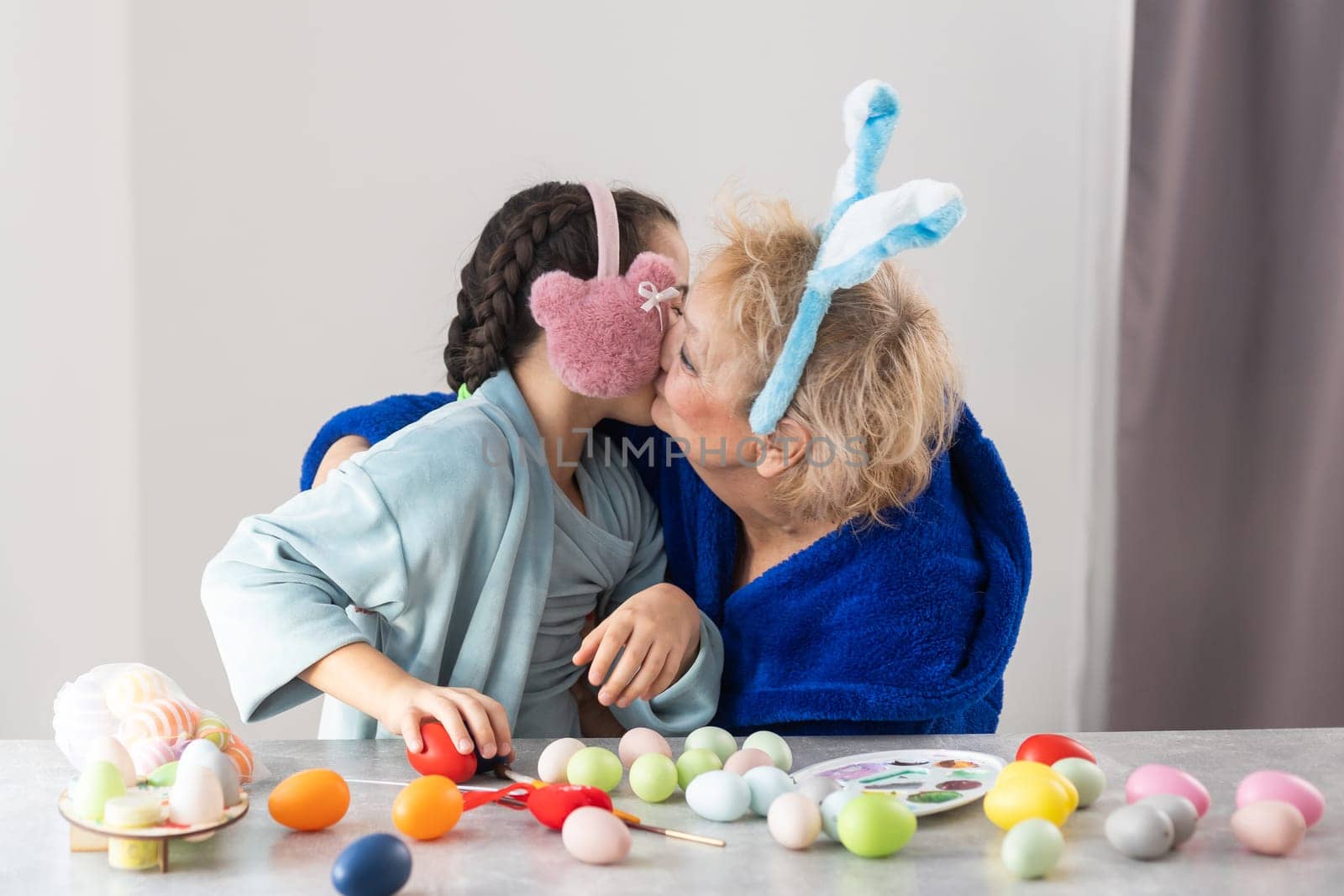 Easter concept. Grandmother with granddaughter are holding Easter eggs at home