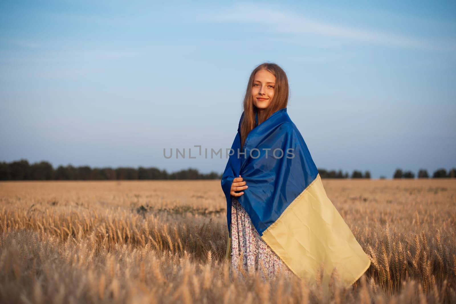 Portrait of a young girl with Ukrainian flag in the field of ripe rye