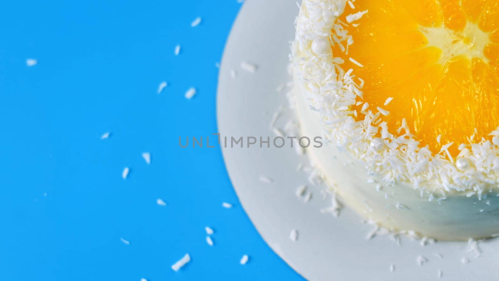 Cake with orange and coconut shavings spinning on a blue background