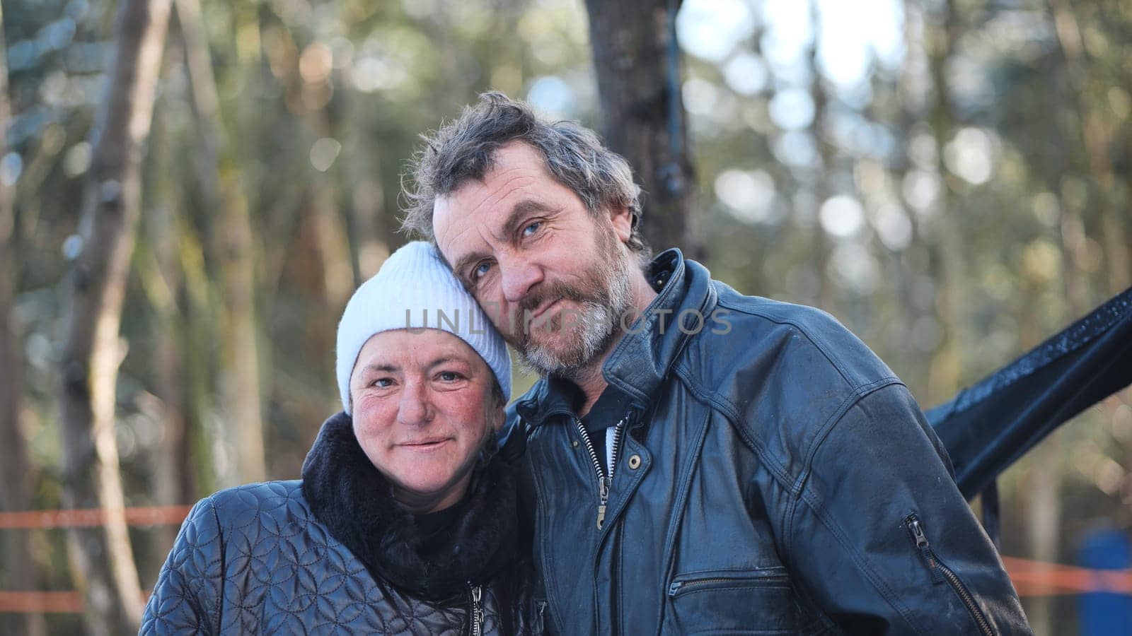 A homeless woman and a man pose in the woods in winter