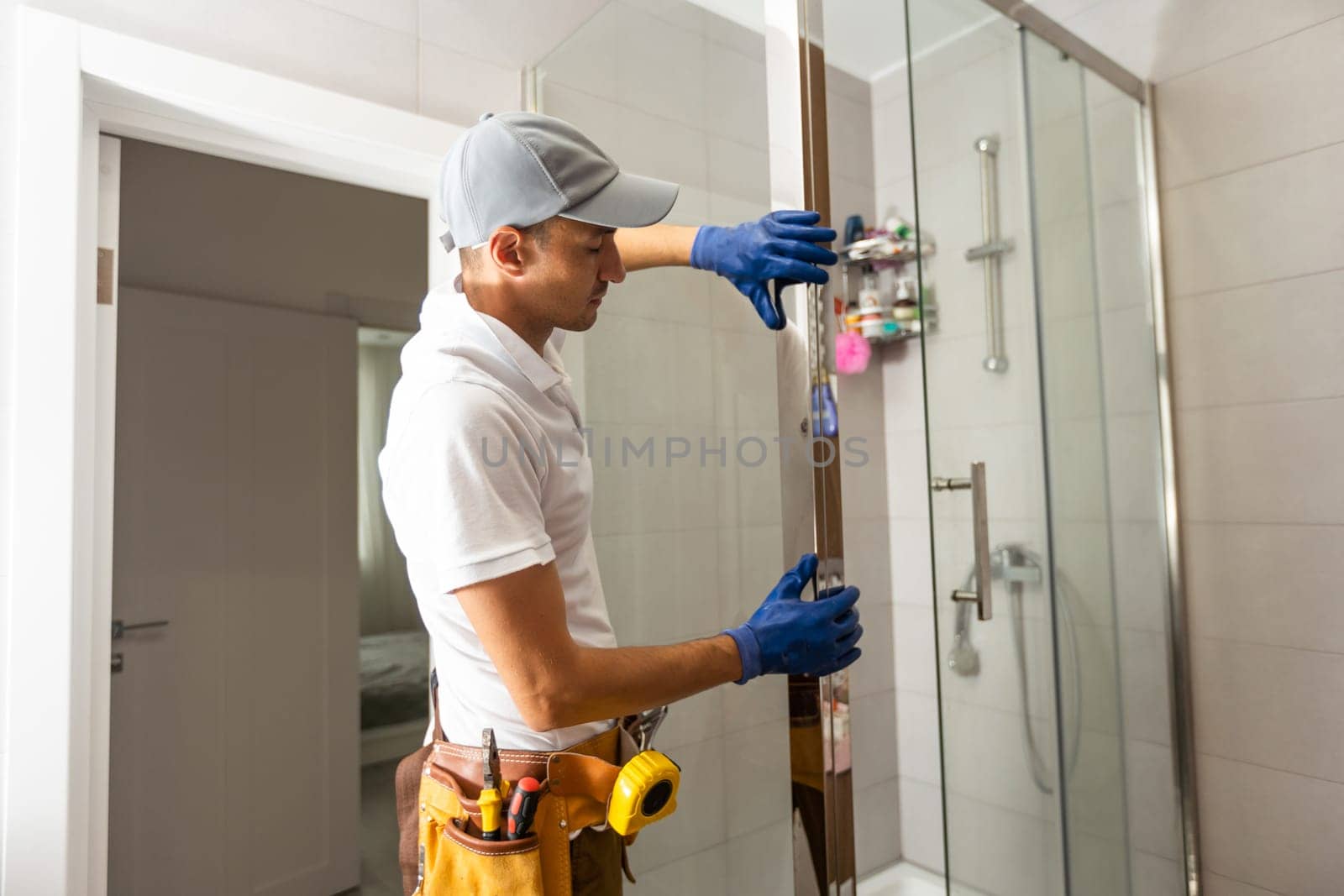 Workers are installing glass door of the shower enclosure by Andelov13