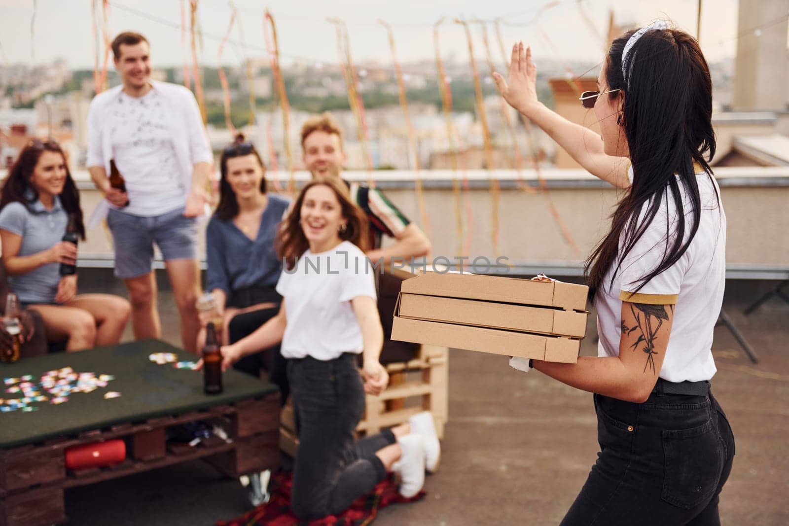 With delicious pizza. Group of young people in casual clothes have a party at rooftop together at daytime.