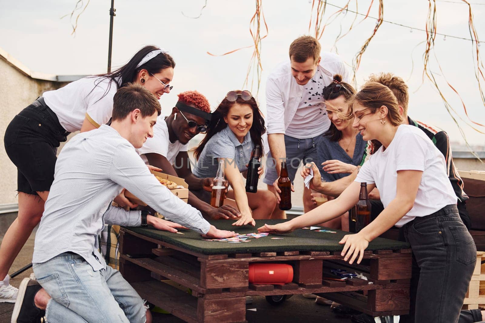 With delicious pizza. Group of young people in casual clothes have a party at rooftop together at daytime.