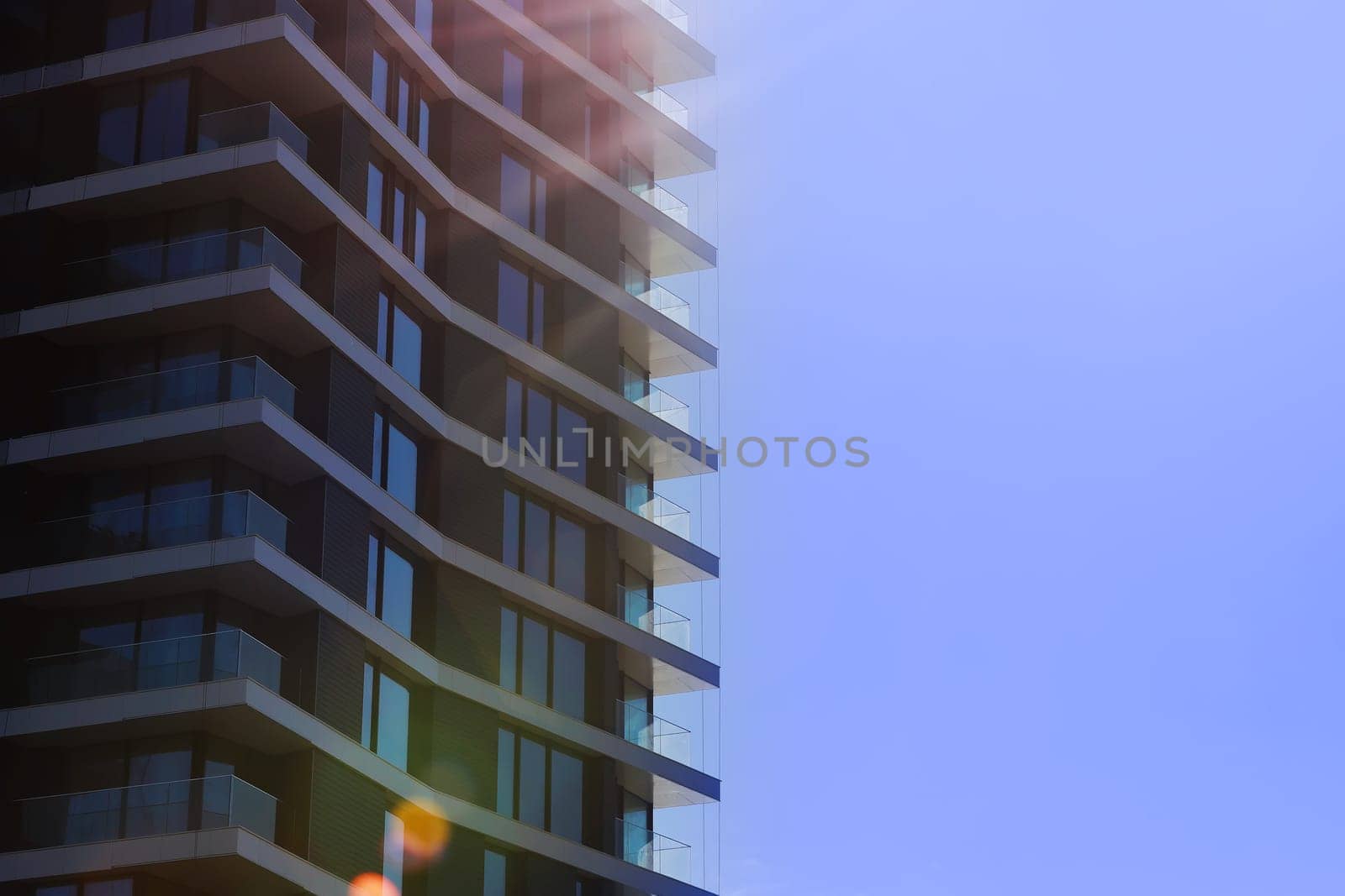 Fragment of modern multi-storey residential building against blue sky. Close-up. Background for ad or banner. Copy space. modern housing. sale of apartments