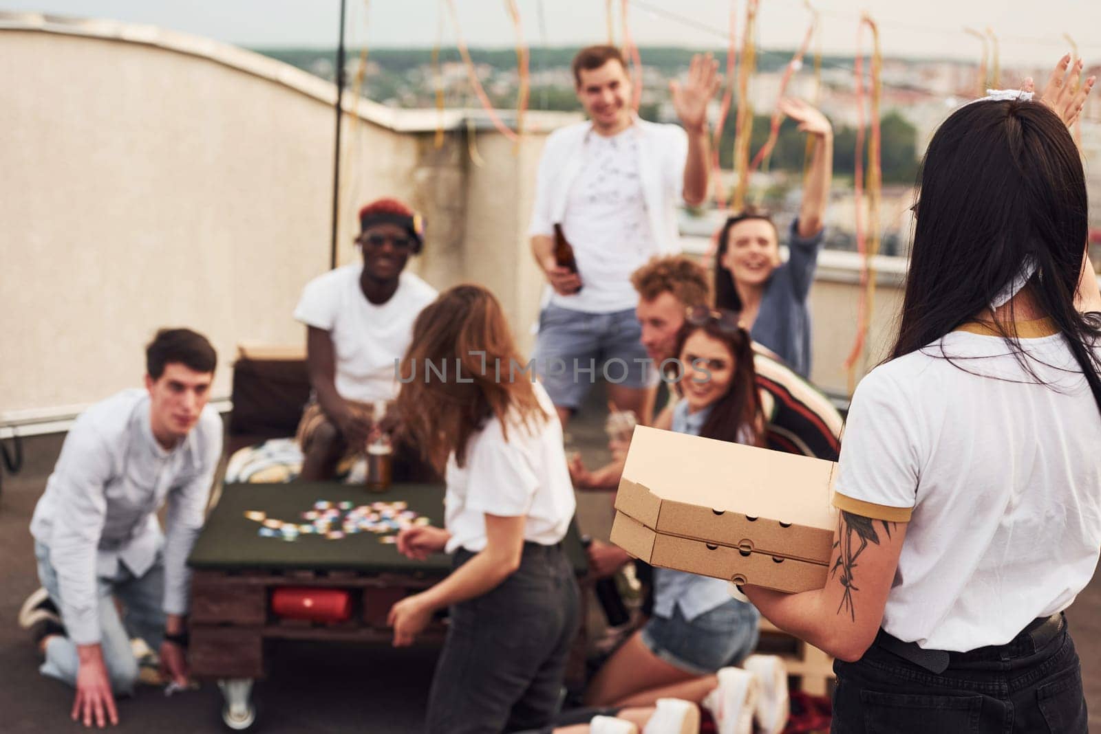 Delicious pizza. Group of young people in casual clothes have a party at rooftop together at daytime.