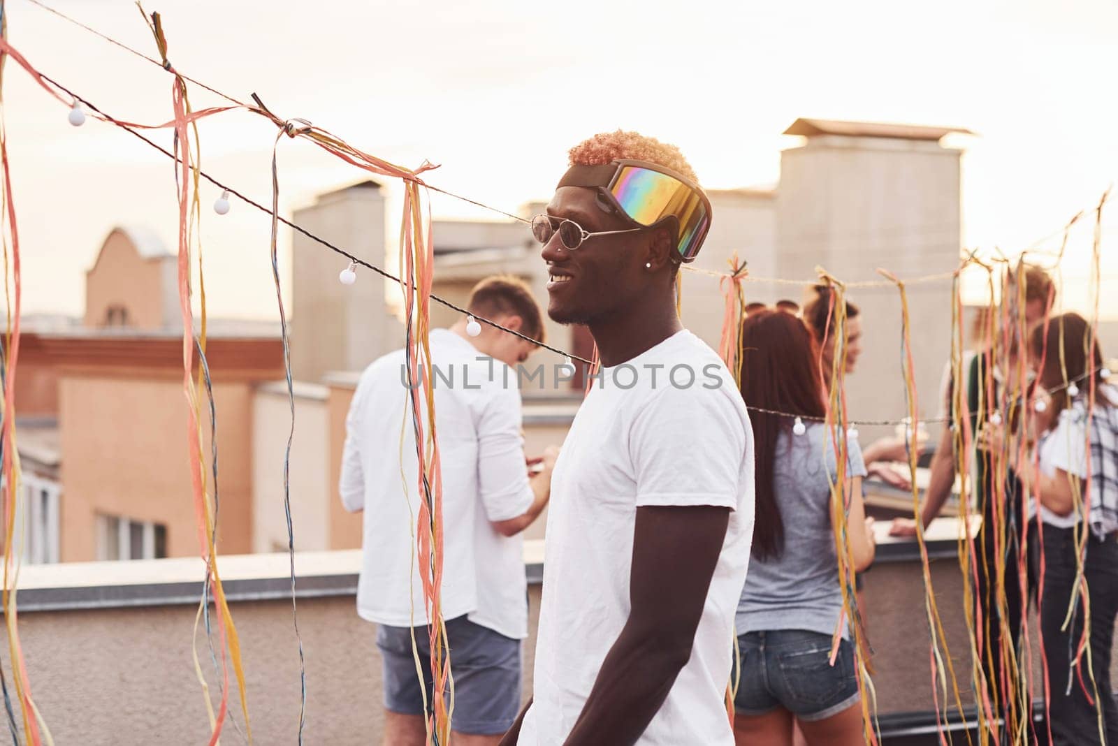 African american man smiling and dancing. Group of young people in casual clothes have a party at rooftop together at daytime.