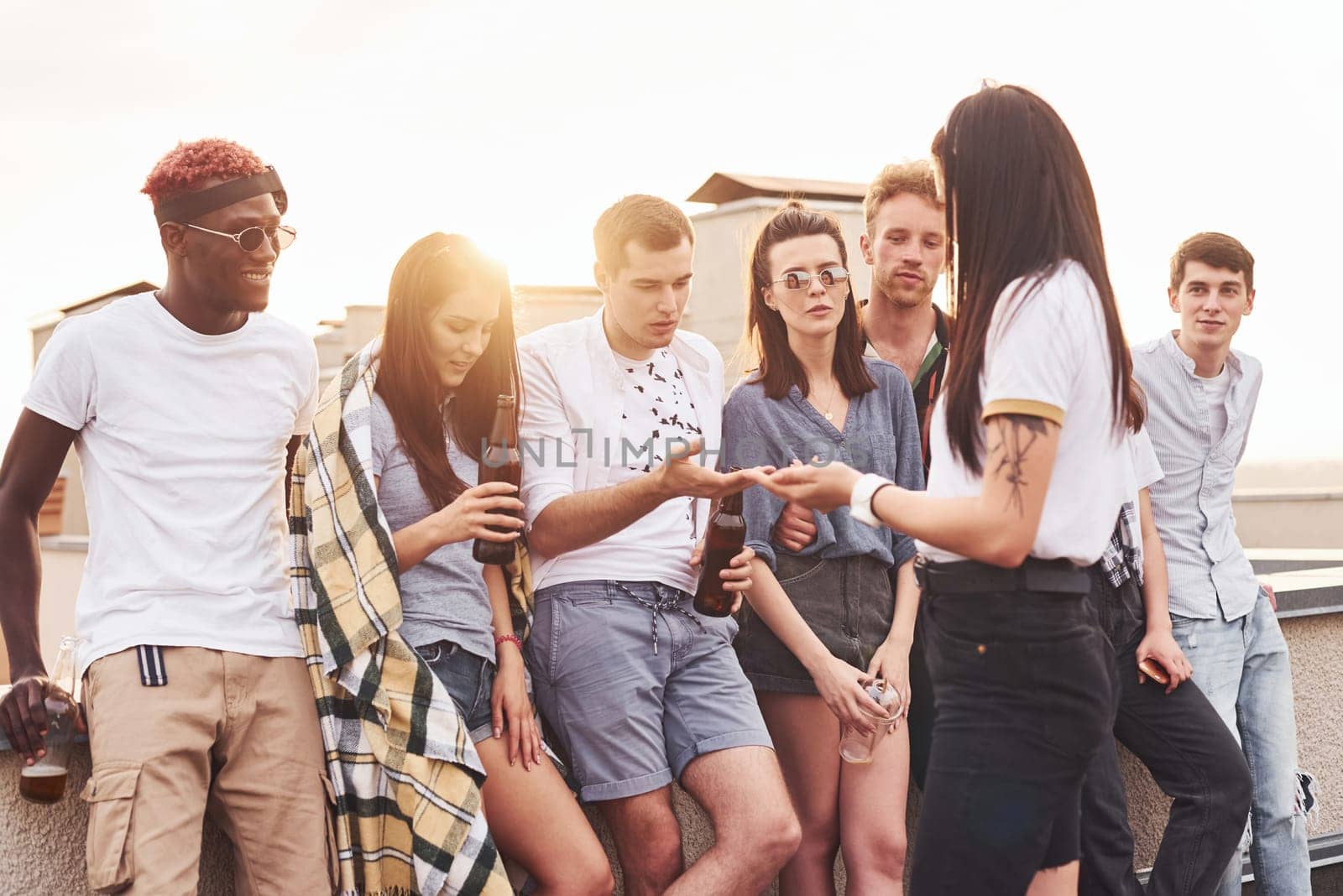 Cloudy weather. Group of young people in casual clothes have a party at rooftop together at daytime.