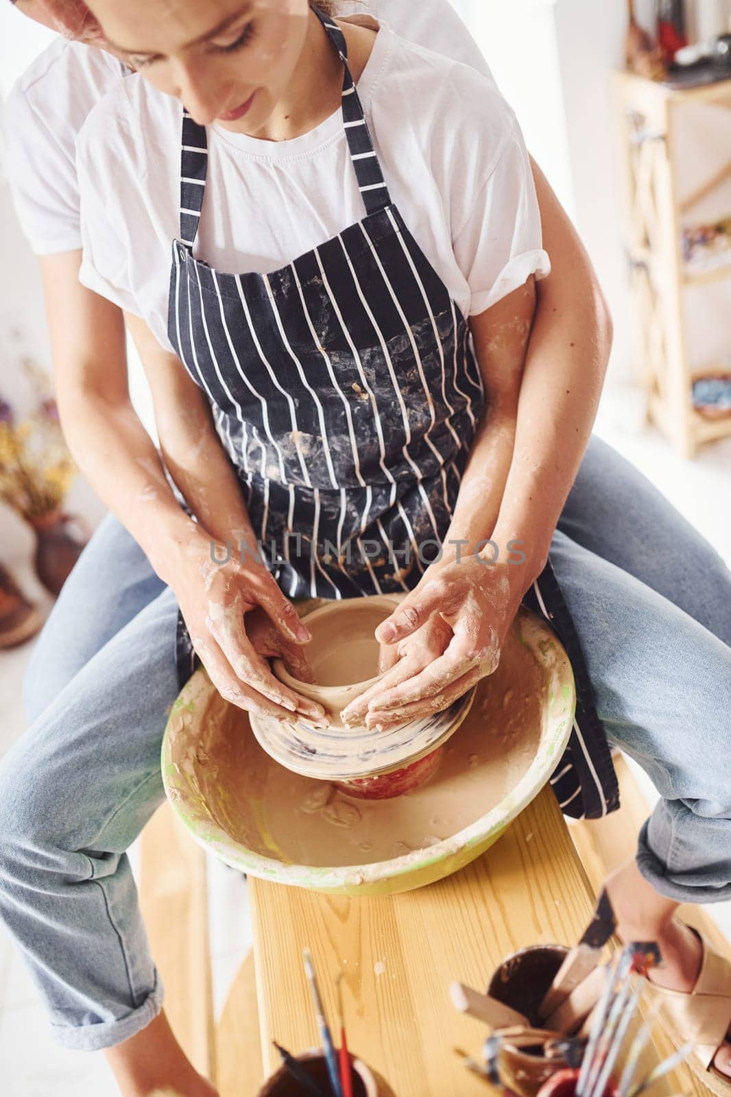 With her boyfriend or husband. Young female ceramist have a works indoors with handmade clay product. Conception of pottery.