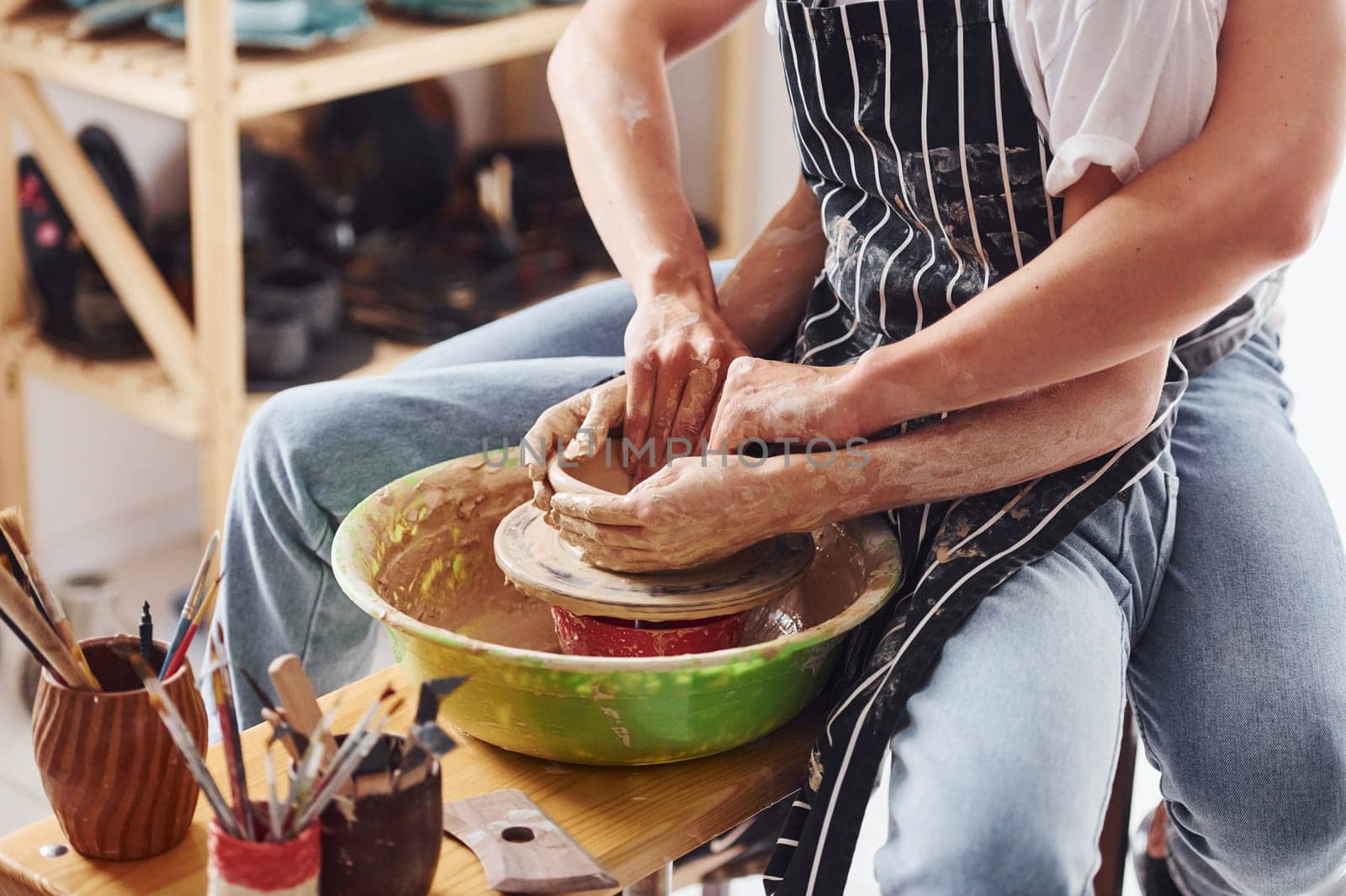With her boyfriend or husband. Close up view of young female ceramist that indoors with handmade clay product. Conception of pottery.