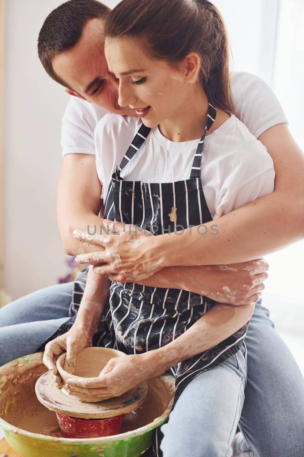 With her boyfriend or husband. Young female ceramist have a works indoors with handmade clay product. Conception of pottery.