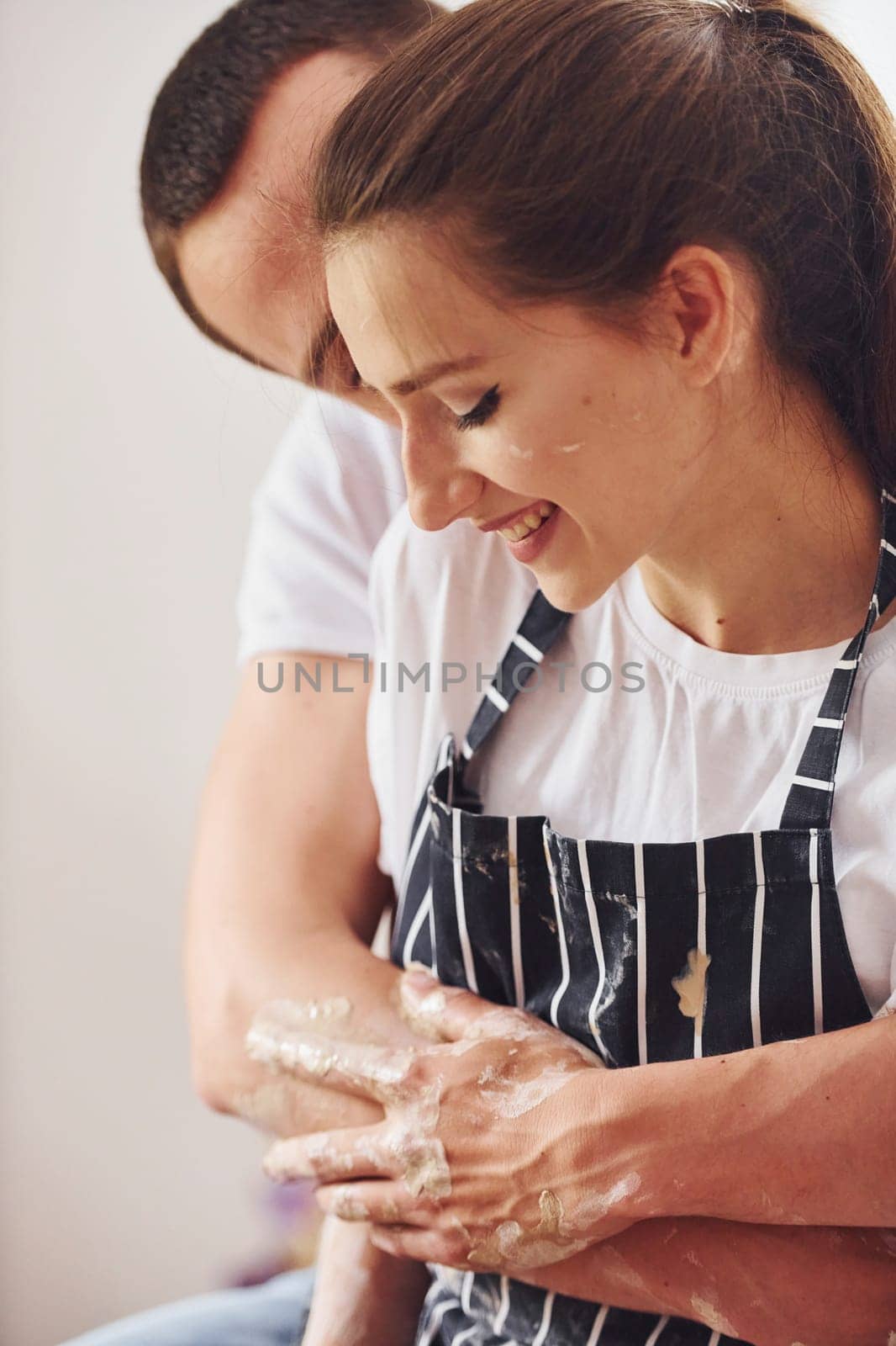 With her boyfriend or husband. Young female ceramist indoors with handmade clay product. Conception of pottery.