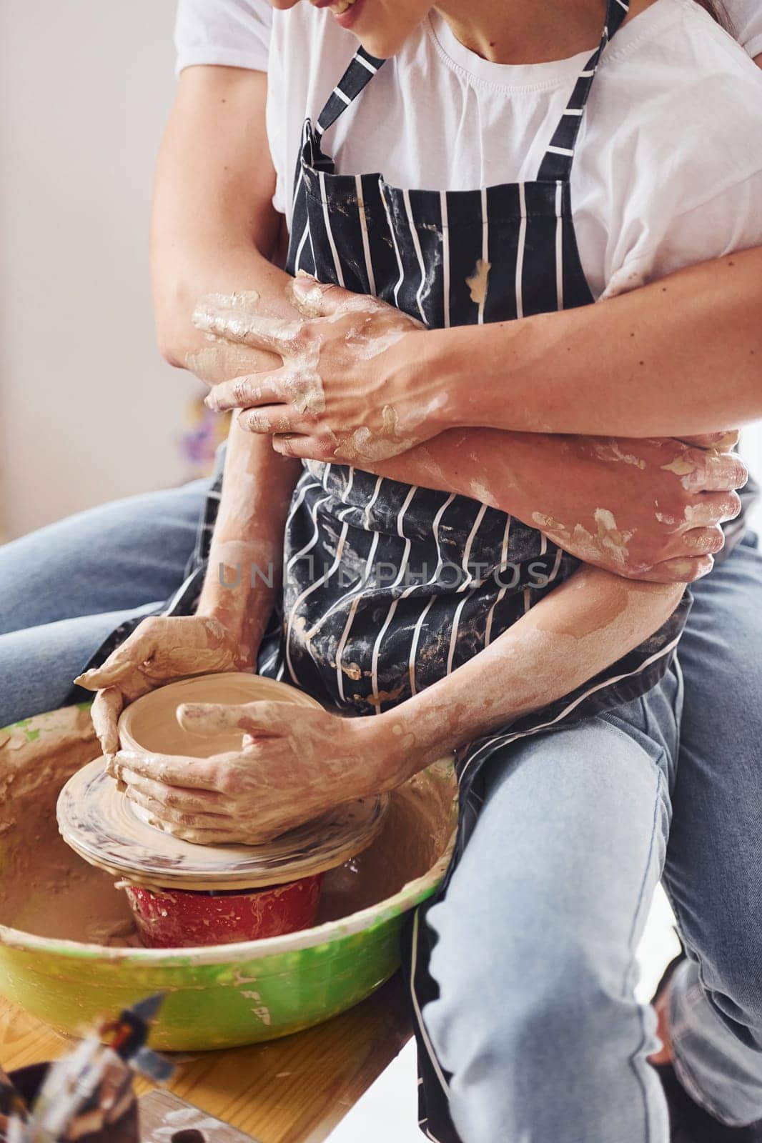 With her boyfriend or husband. Close up view of young female ceramist that indoors with handmade clay product. Conception of pottery.