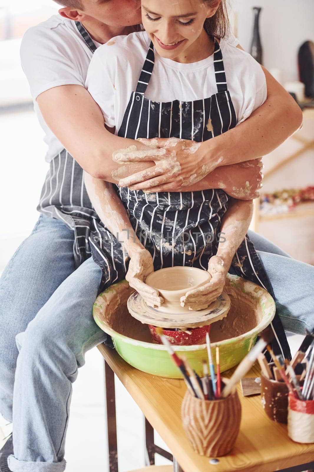With her boyfriend or husband. Young female ceramist have a works indoors with handmade clay product. Conception of pottery.