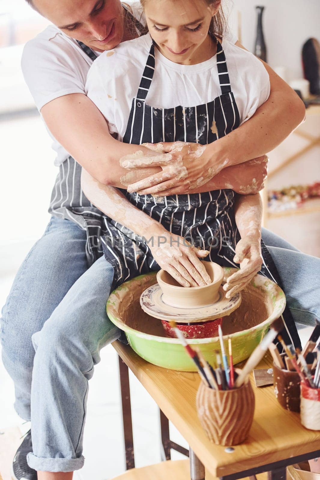 With her boyfriend or husband. Young female ceramist indoors with handmade clay product. Conception of pottery.