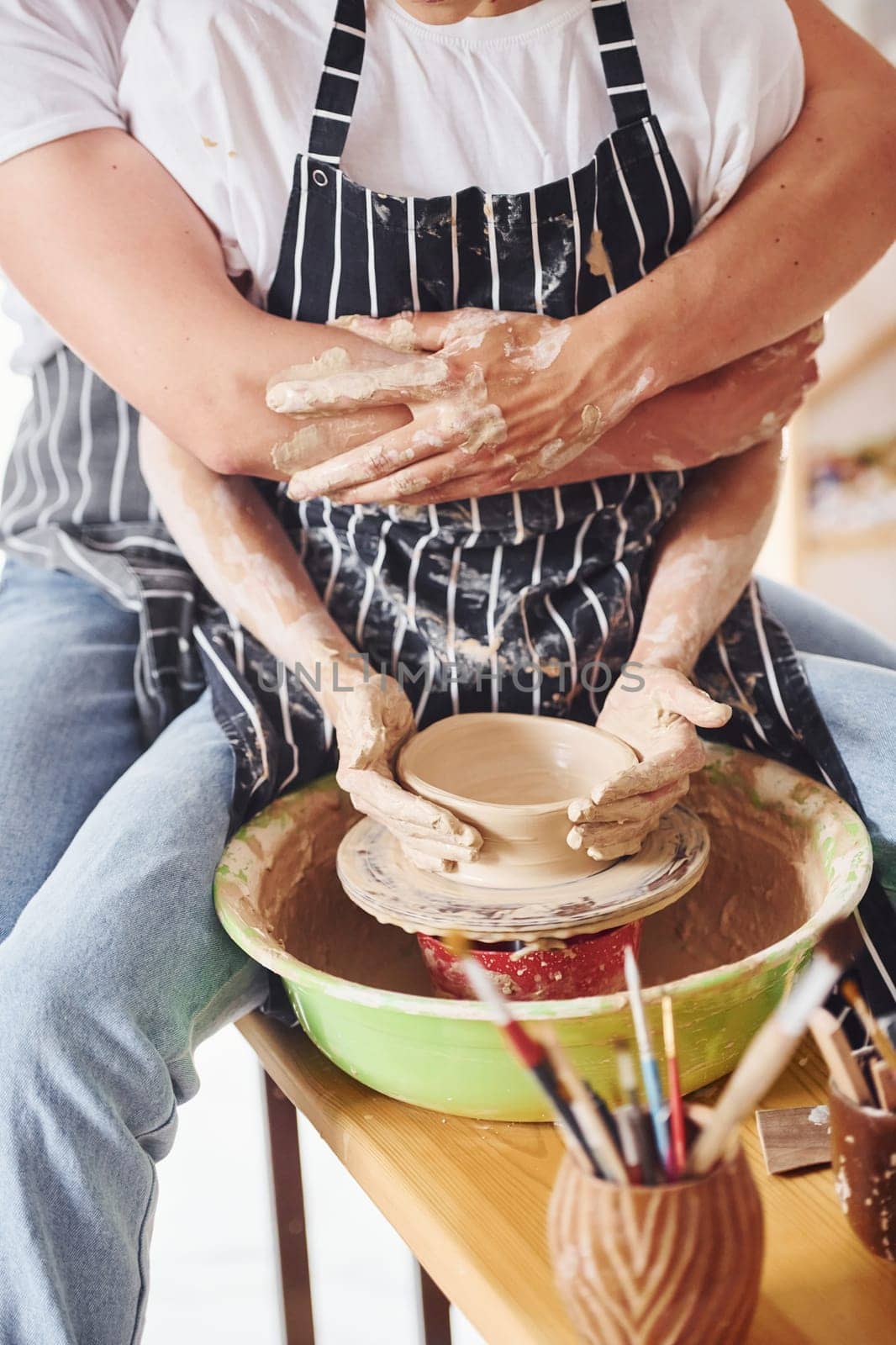 With her boyfriend or husband. Close up view of young female ceramist that indoors with handmade clay product. Conception of pottery.