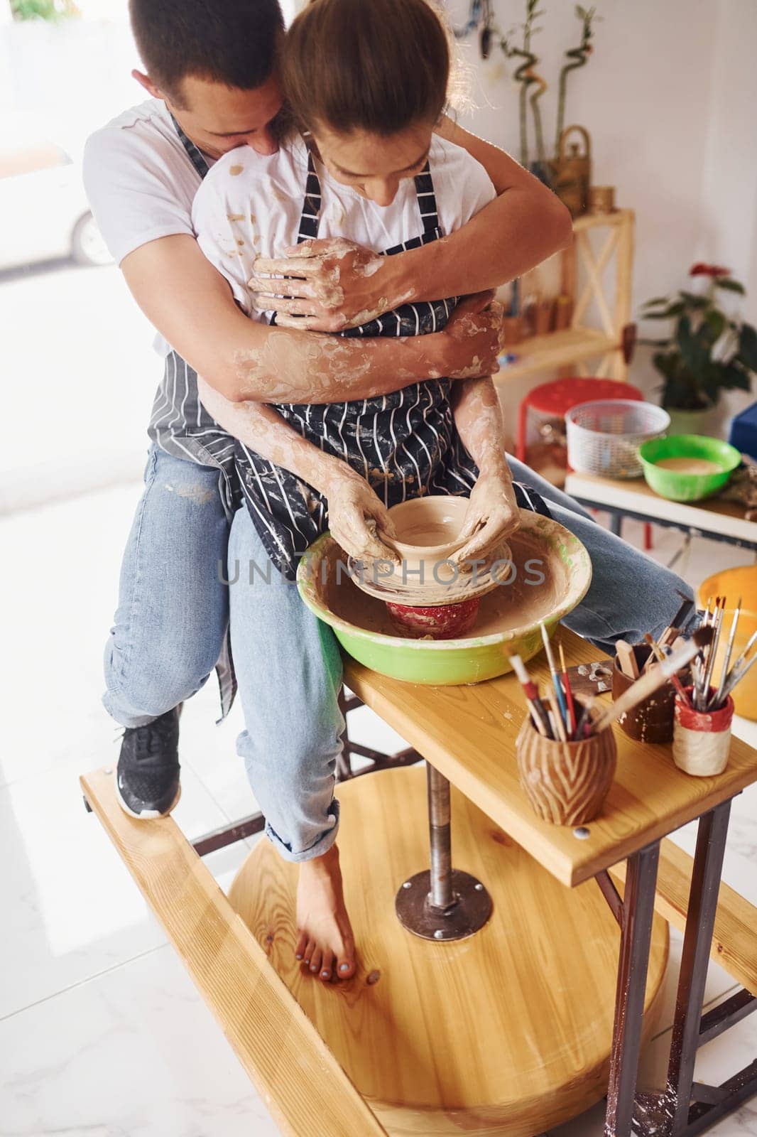 With her boyfriend or husband. Young female ceramist indoors with handmade clay product. Conception of pottery.