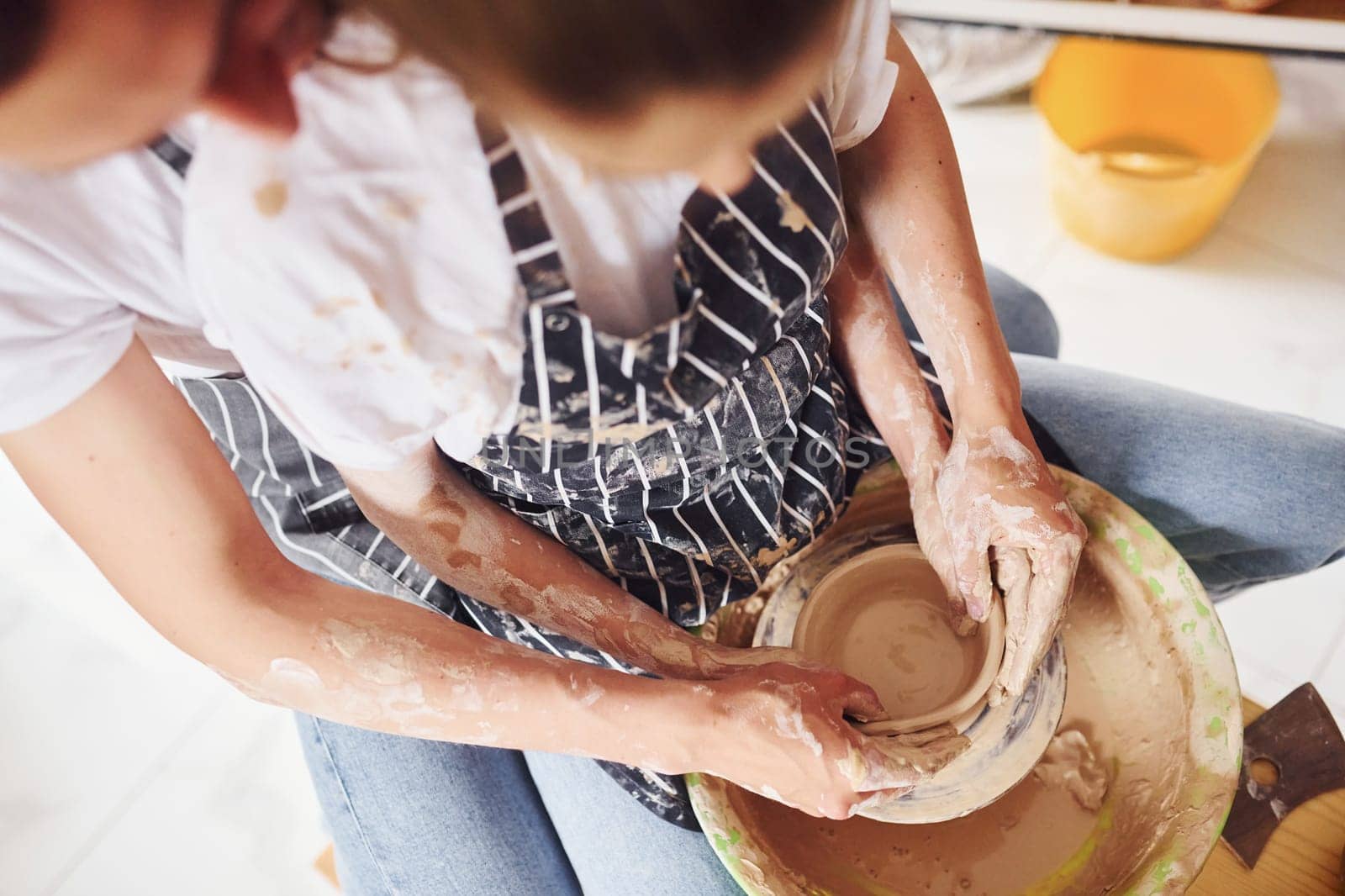 With her boyfriend or husband. Close up view of young female ceramist that indoors with handmade clay product. Conception of pottery.