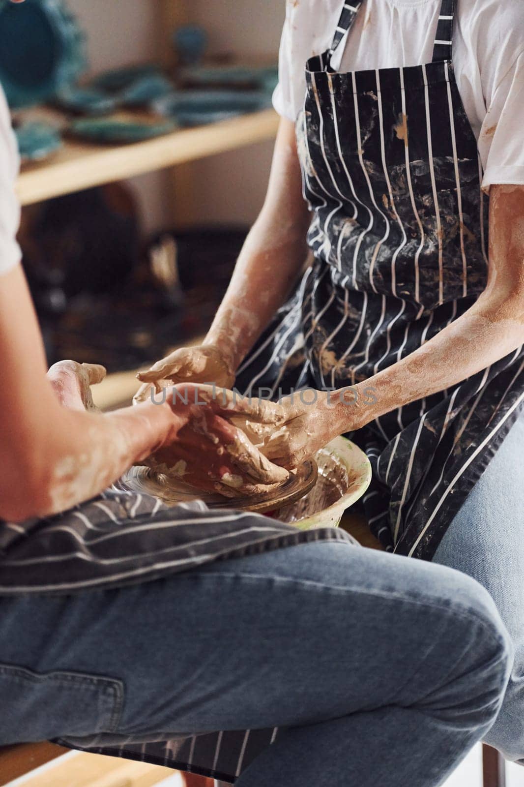 With her boyfriend or husband. Close up view of young female ceramist that indoors with handmade clay product. Conception of pottery.
