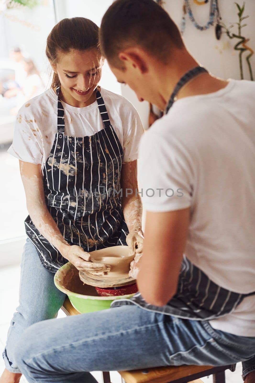 With her boyfriend or husband. Young female ceramist indoors with handmade clay product. Conception of pottery.