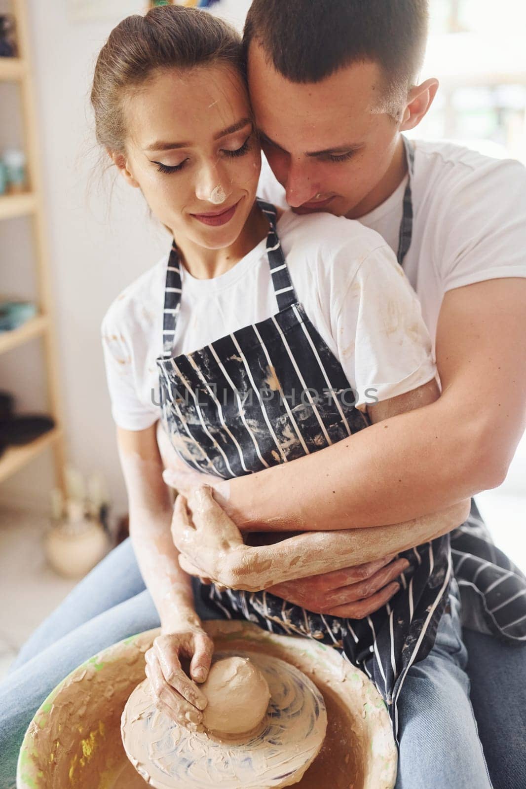 With her boyfriend or husband. Young female ceramist indoors with handmade clay product. Conception of pottery.