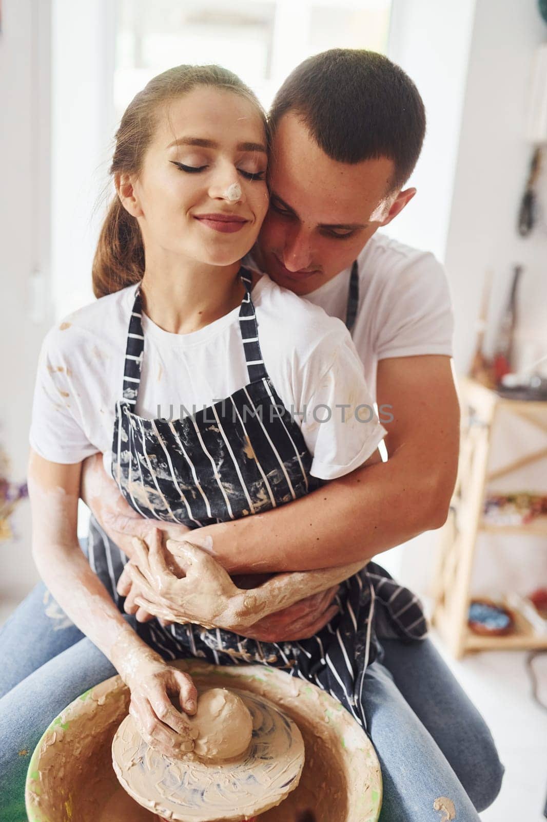 With her boyfriend or husband. Young female ceramist indoors with handmade clay product. Conception of pottery.
