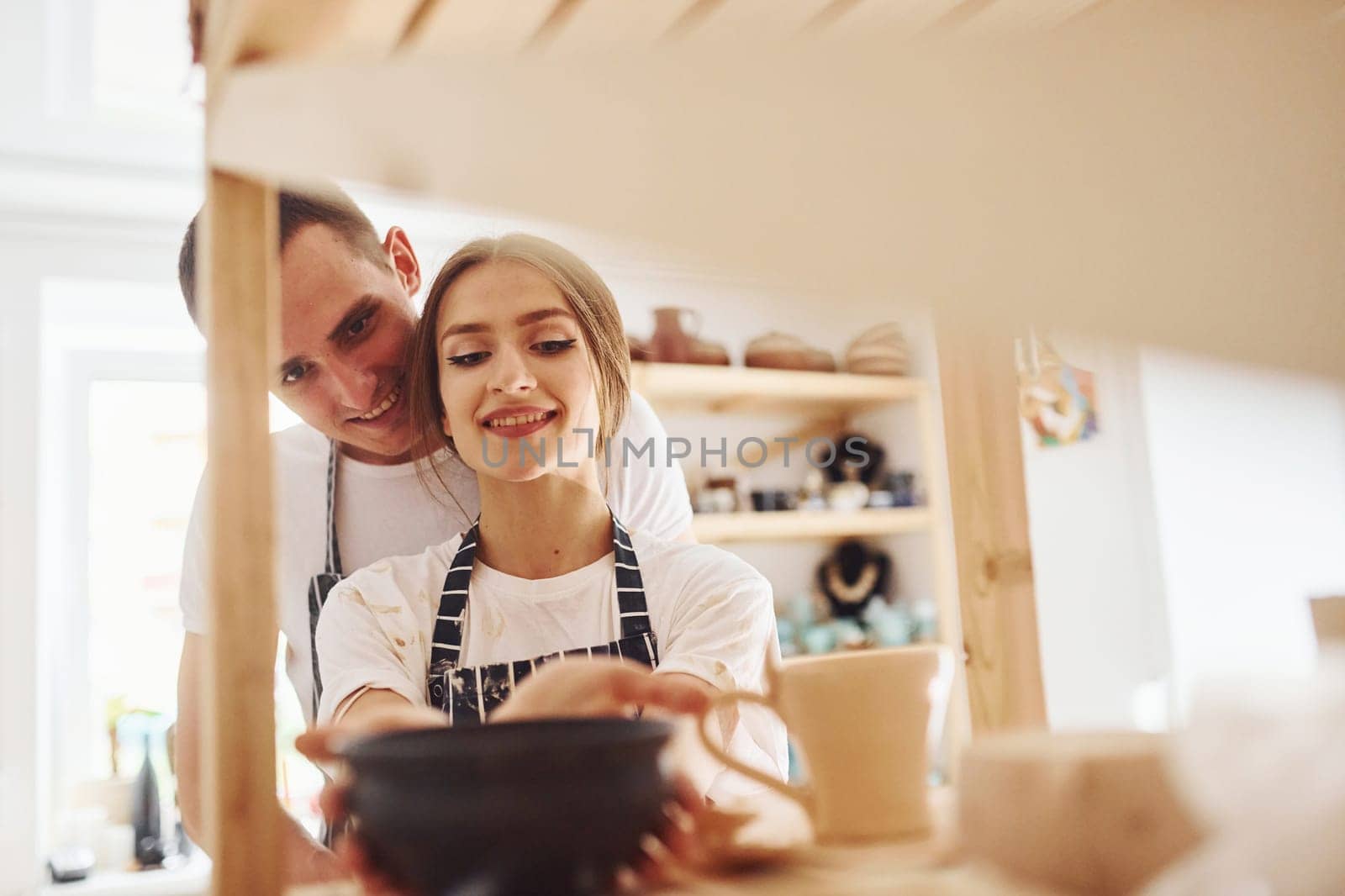 Job is done. With her boyfriend or husband. Young female ceramist indoors with finished handmade clay product. Conception of pottery.