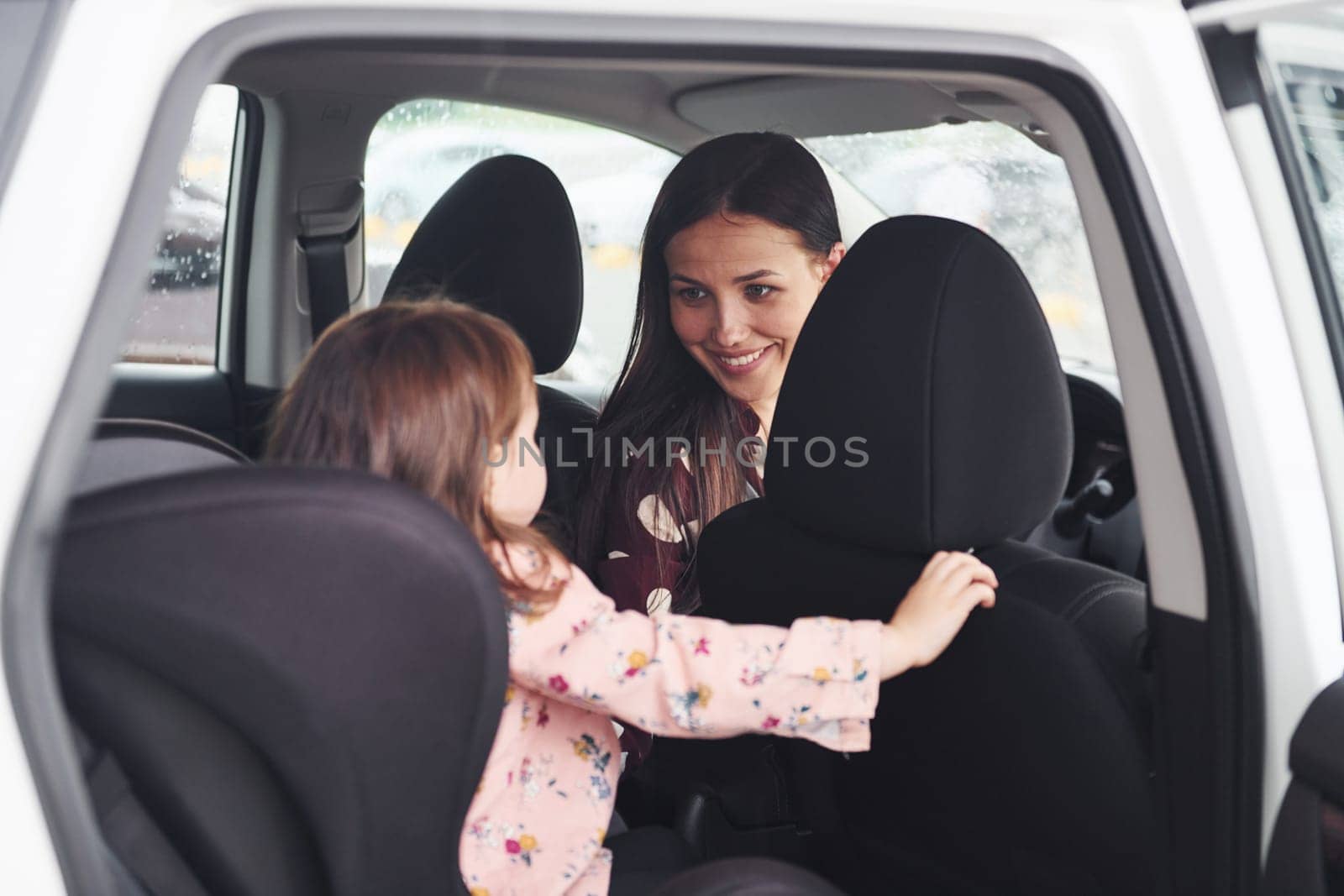 Mother with her daughter inside of modern automobile together.