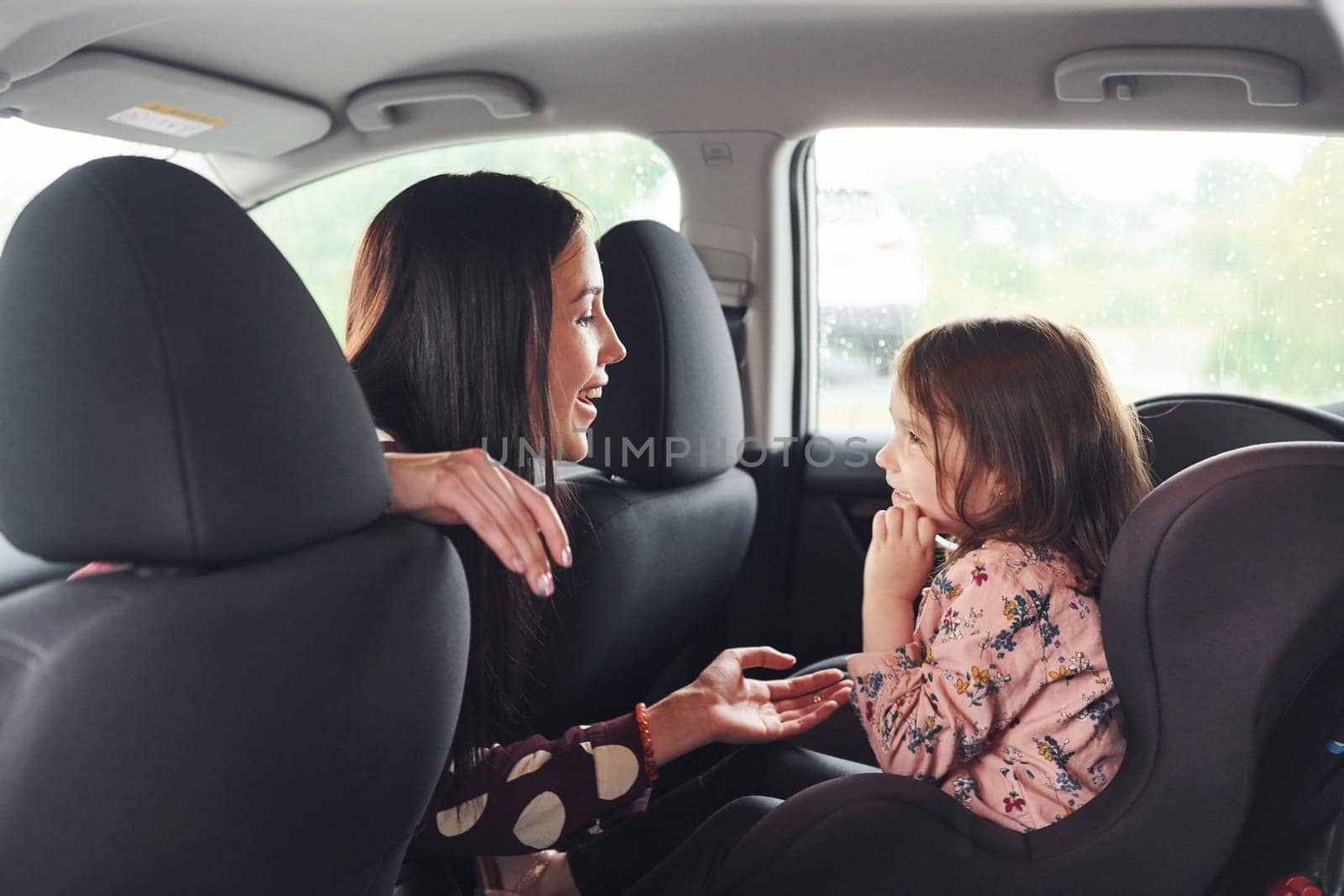 Mother with her daughter inside of modern automobile together.