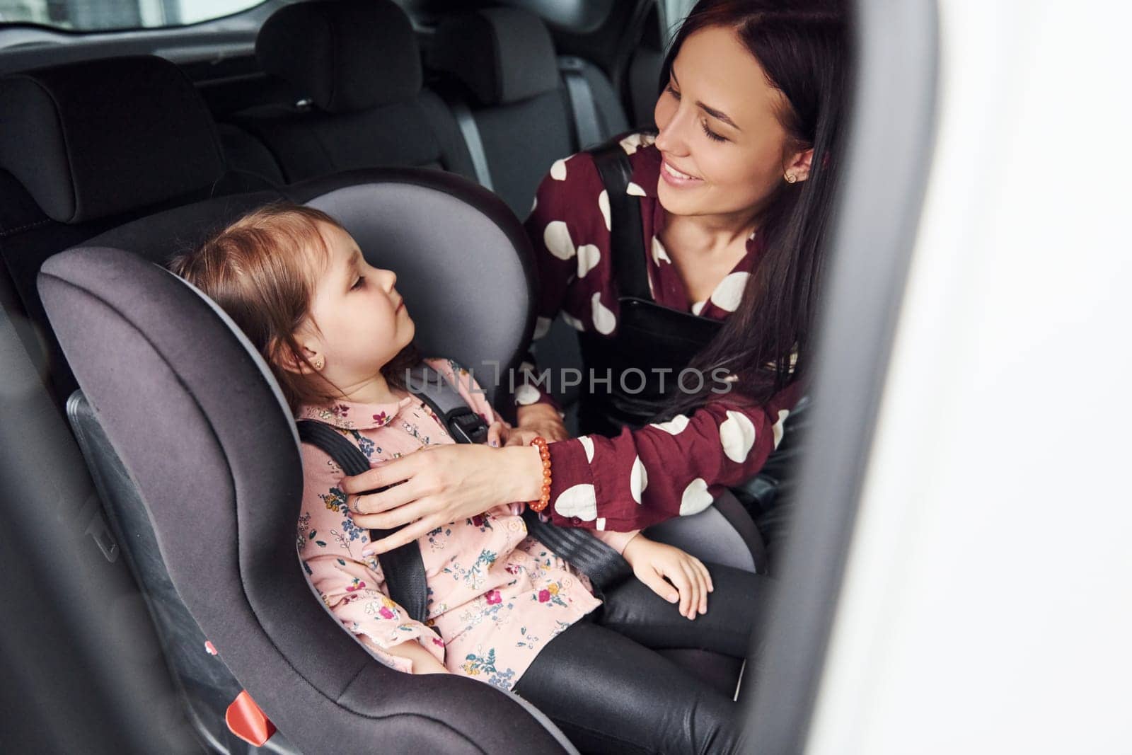 Mother with her daughter inside of modern automobile together.