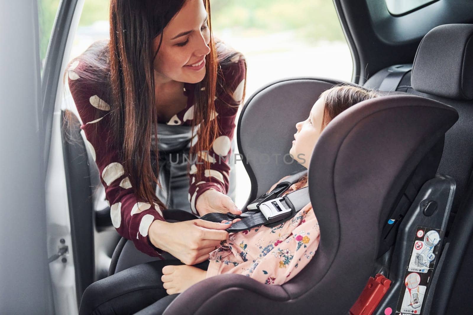 Mother with her daughter inside of modern automobile together.
