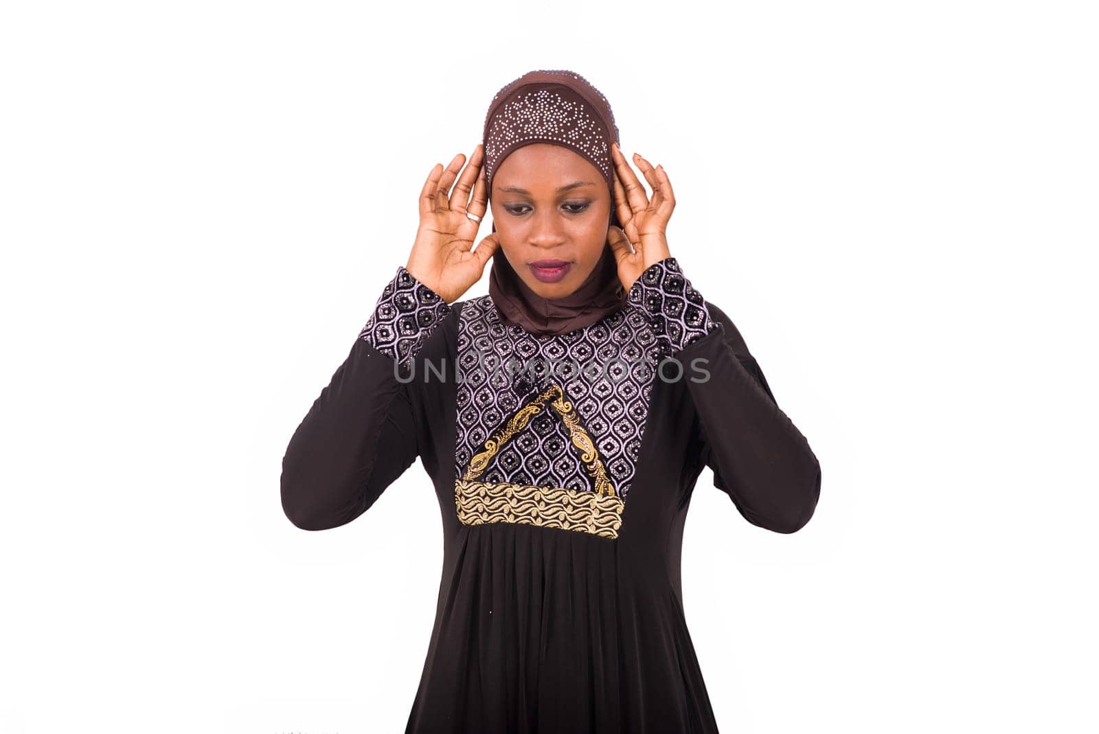 young muslim woman standing in long dress in prayer position.