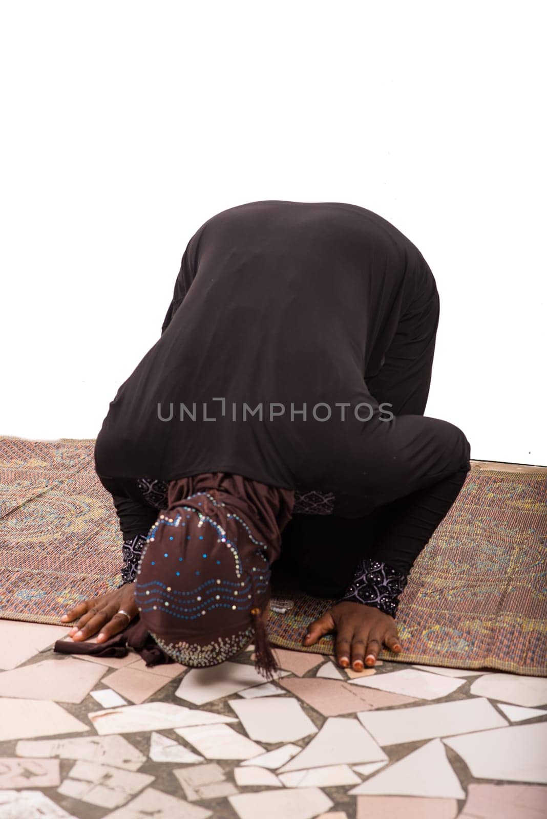 young muslim woman in long dress on mat praying.