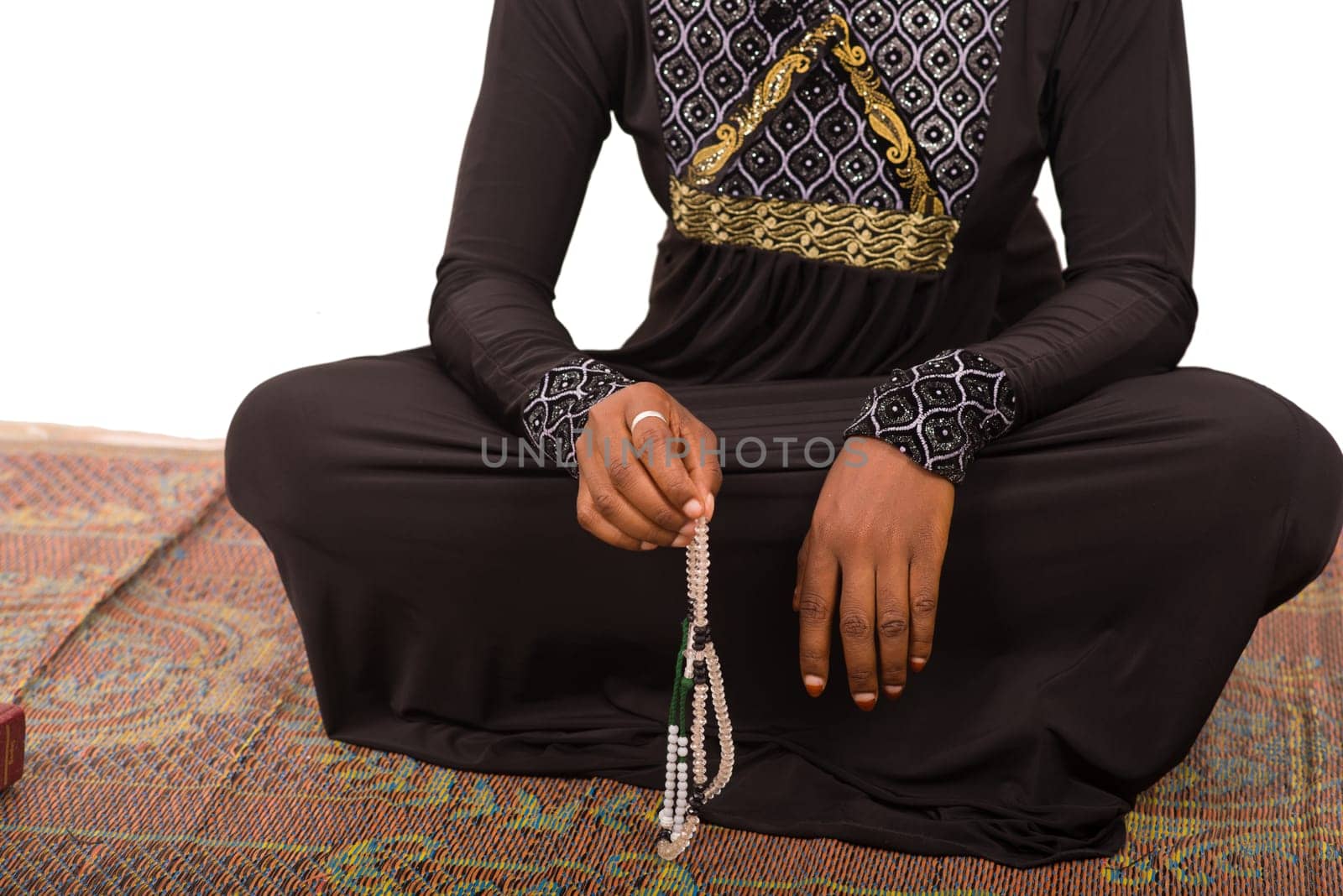 young muslim woman sitting in long dress on mat praying.