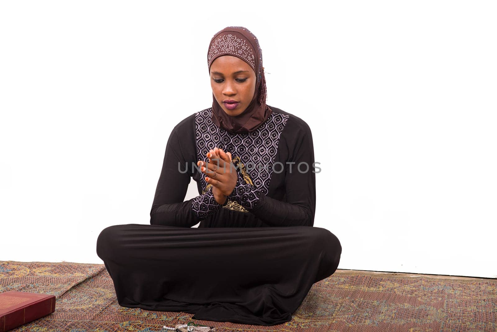 young muslim woman sitting on a mat praying.