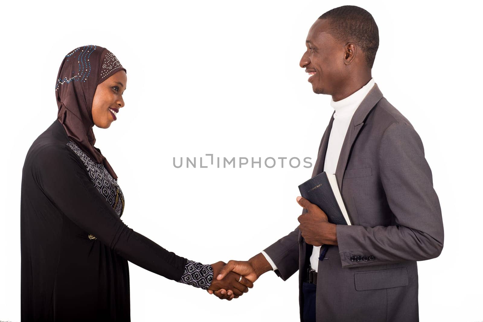 Young religious standing shaking hands smiling.