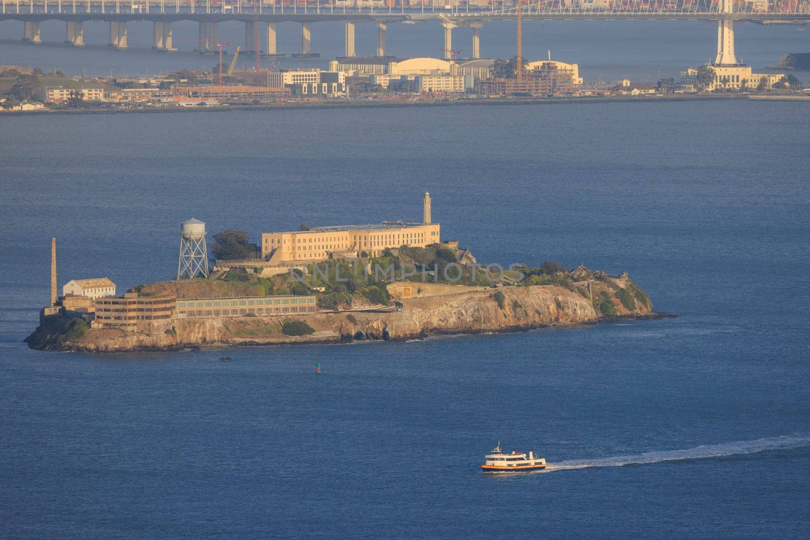 Alcatraz Island and sightseeing ferry in San Francisco Bay at Golden Hour. High quality photo