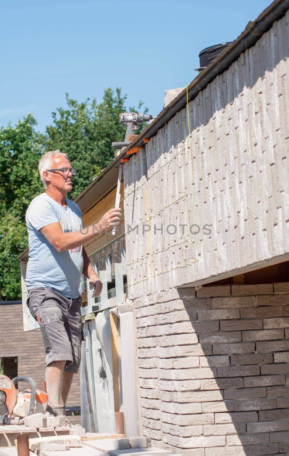 the bricklayer makes the facade of the house from gray bricks with cement and plaster at the construction site. High quality photo