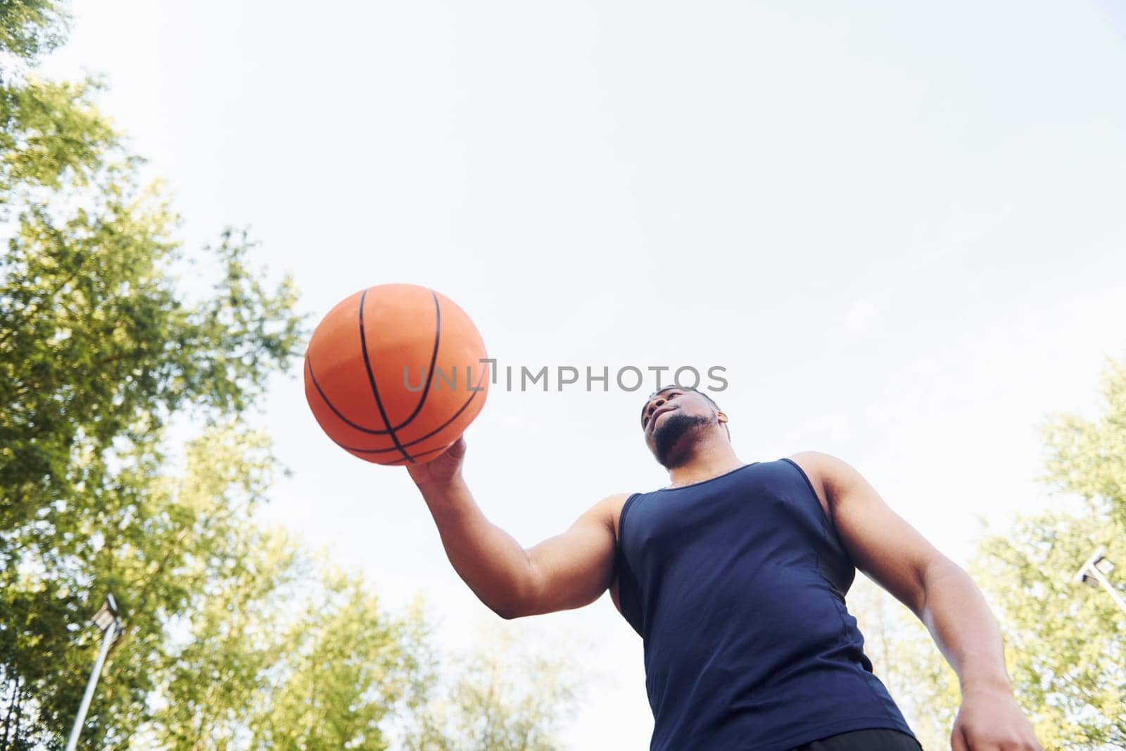 Cloudy weather. African american man plays basketball on the court outdoors.
