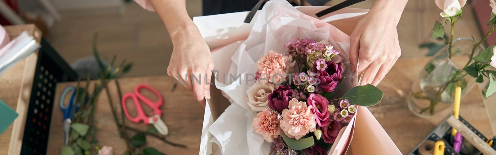 Professional florist young woman is doing bouquets at flower shop by Yaroslav_astakhov