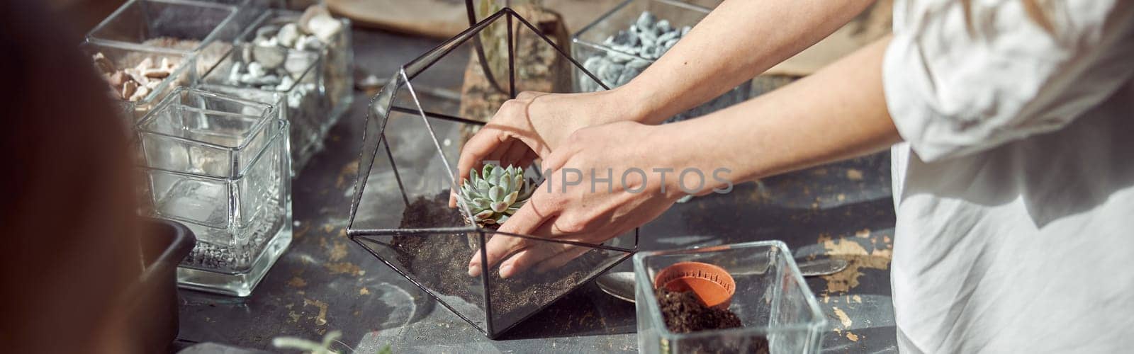 caucasian confident happy florist is working with her young daughter and making composition from glass stones and plants in botanic shop by Yaroslav_astakhov
