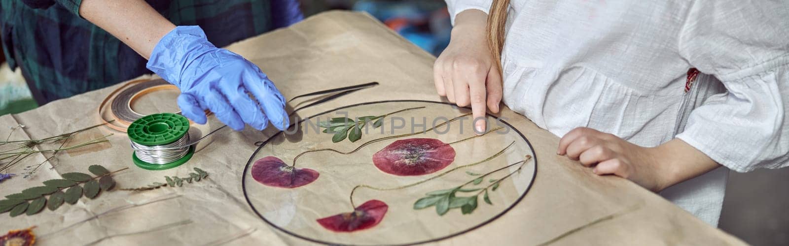 Flourist shop with different kinds of dryed flowers. Young happy confident specialist is working with her female kid.