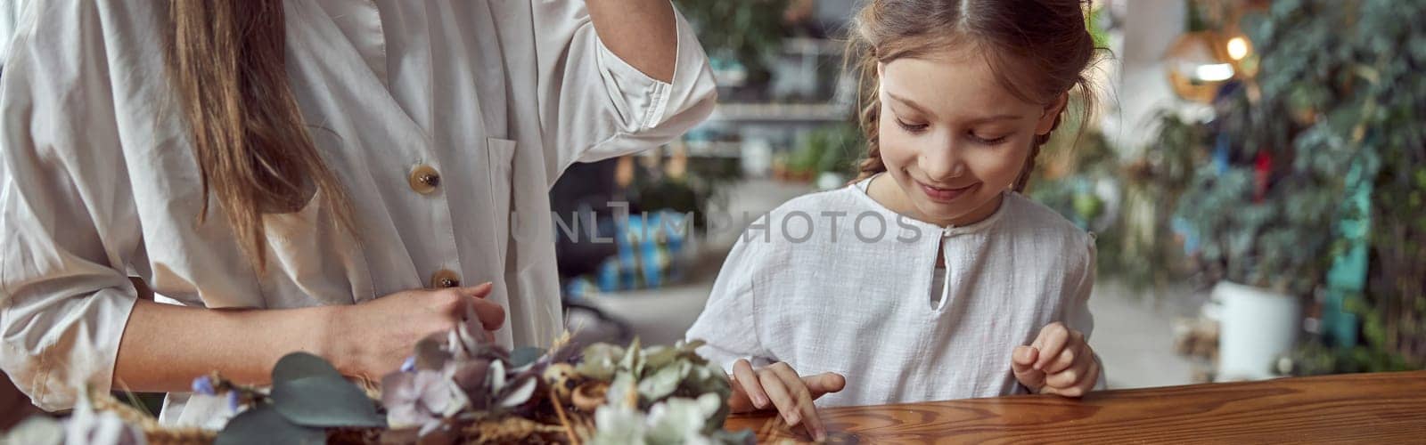 Flourist shop with different kinds of dryed flowers. Young happy confident specialist is working with her female kid. by Yaroslav_astakhov